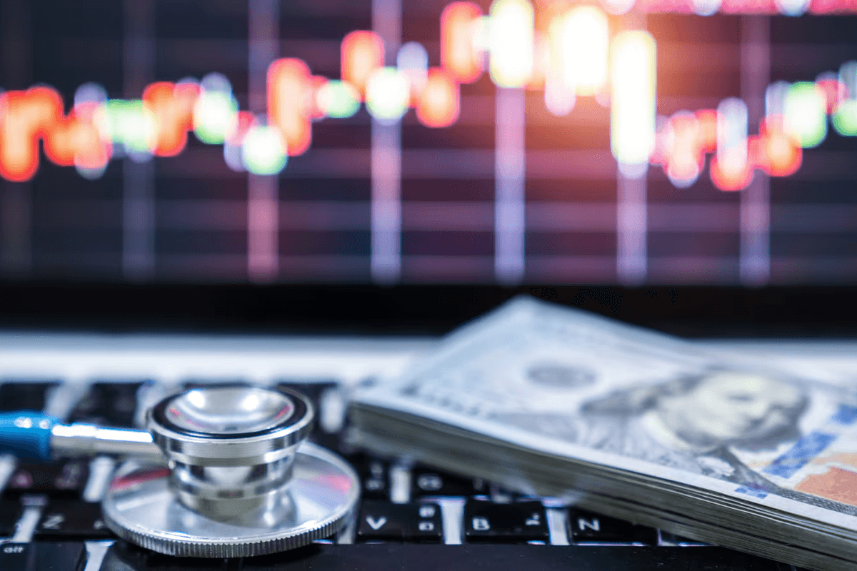 A stethoscope on a keyboard in front of healthcare market data charts